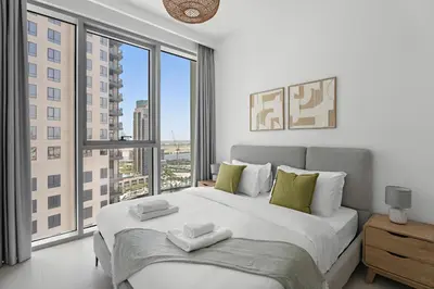 a bedroom with a large bed with a large window at Vayk - Bright & Elegant 2BR Apartment with Creek Views in Dubai