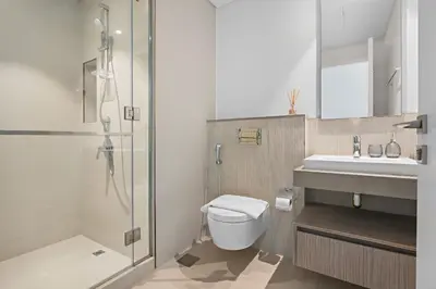 a bathroom with a shower and a toilet and a sink at Vayk - Bright & Elegant 2BR Apartment with Creek Views in Dubai