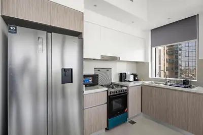 a kitchen with a stainless steel refrigerator and a sink at Vayk - Bright & Elegant 2BR Apartment with Creek Views in Dubai
