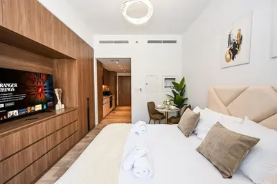 a bedroom with a large white bed and a television at Golden Stays - Brand New JVC Studio I Modern & Fully Furnished in Dubai
