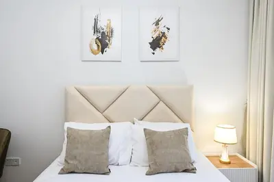 a bed with white sheets and pillows in a bedroom at Golden Stays - Brand New JVC Studio I Modern & Fully Furnished in Dubai