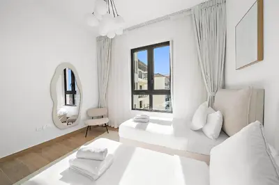 a white bedroom with a bed and a mirror at VayK - Modern 2BR with Stunning Sea View in Port de La Mer in Dubai