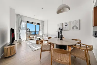 a living room with a table and chairs and a television at VayK - Modern 2BR with Stunning Sea View in Port de La Mer in Dubai