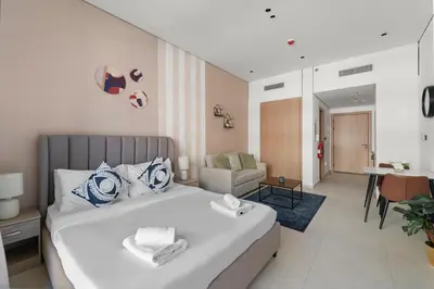 a bedroom with a bed and a living room at VayK - Contemporary and Cozy Studio in the Heart of JVC in Dubai