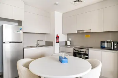 a white kitchen with a white table and chairs at VayK - Stunning 1BR with Breathtaking Views in Dubai