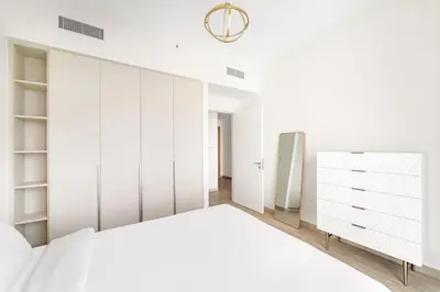 a white bedroom with a bed and a closet at VayK - Stunning 1BR with Breathtaking Views in Dubai