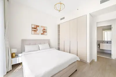 a white bedroom with a large bed and a bathroom at VayK - Stunning 1BR with Breathtaking Views in Dubai
