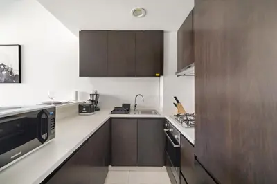 a kitchen with wooden cabinets and a microwave at VayK - Modern 1BR Apartment in Business Bay in Dubai