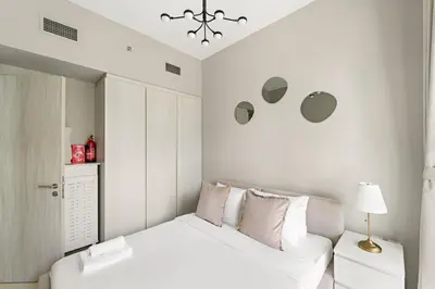 a white bedroom with a bed and a chandelier at VayK - Stylish 1BR in Business Bay in Dubai