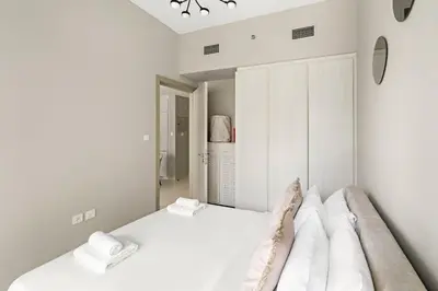 a white bedroom with a bed and a closet at VayK - Stylish 1BR in Business Bay in Dubai