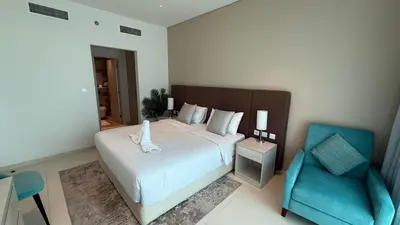 a bedroom with a bed and a blue chair at Highend Seven Palm 1BR Private Beach and Infinity Pool in Dubai