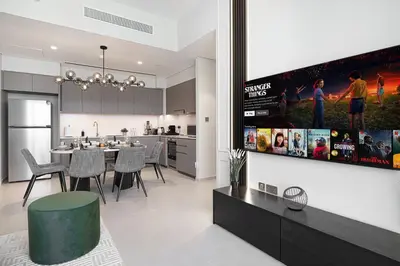 a kitchen and living room with a tv on a wall at SkyHigh Luxury 2BR Burj View Private Hot Tub Walk to DubaiMall in Dubai