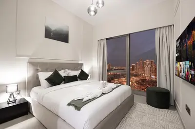 a bedroom with a large white bed with a large window at SkyHigh Luxury 2BR Burj View Private Hot Tub Walk to DubaiMall in Dubai