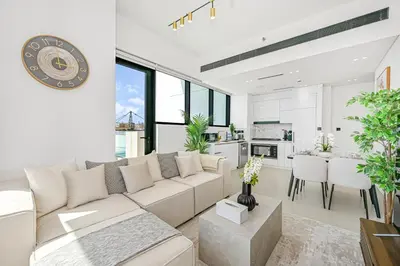 a living room with a white couch and a kitchen at Stunning 2BDR Luxury Private Pool and Terrace in Dubai