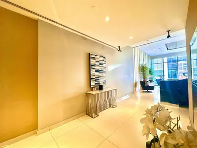a lobby with yellow walls and a table and flowers at Bright & Airy 2BR Full Park View in Dubai
