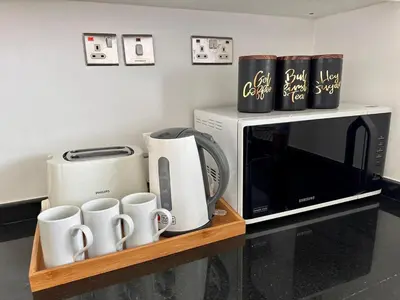 a microwave and coffee cups on a wooden shelf at Bright & Airy 2BR Full Park View in Dubai