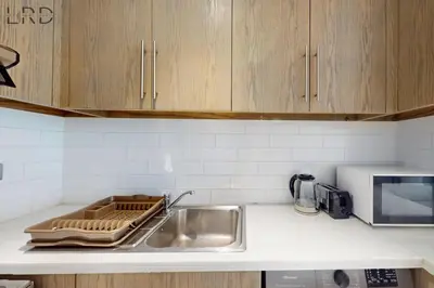 a kitchen counter with a sink and a microwave at Brand New & Modern 1BR Apartment in Dubai