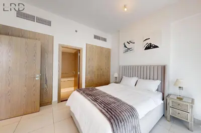 a bedroom with a white bed and a wooden door at Brand New & Modern 1BR Apartment in Dubai