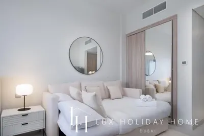 a white bedroom with a white couch and a mirror at LUX Dubai Hills Sway Studio 2 in Dubai