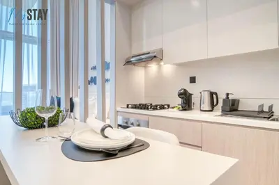 a white kitchen with a table with a wine glass at Luxurious Spacious Studio in Dubai