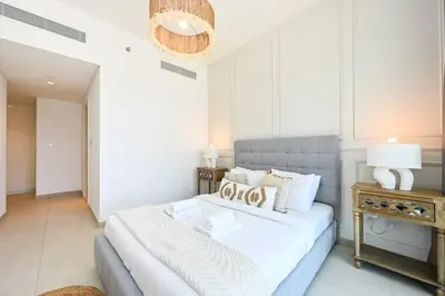 a bedroom with a large bed and a table at DTV 2BR Burj View, Pool in Dubai