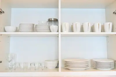 a white cabinet filled with plates and bowls at DTV 2BR Burj View, Pool in Dubai