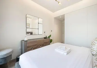 a white bedroom with a bed and a mirror at Waterfront 1BR - Canal View - Fully Furnished in Dubai