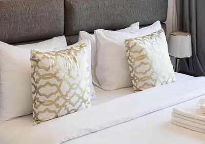 a bed with white pillows and a gray headboard at Waterfront 1BR - Canal View - Fully Furnished in Dubai