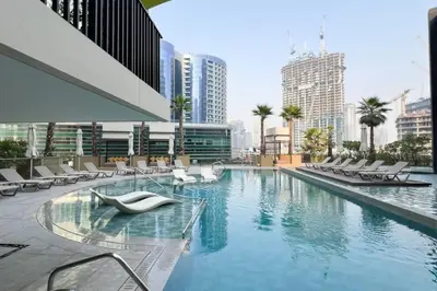 a swimming pool with lounge chairs in a city at Waterfront 1BR - Canal View - Fully Furnished in Dubai