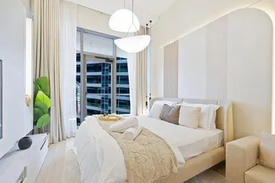 a white bedroom with a large bed and a window at Tranquil Haven Near Burj Khalifa in Dubai