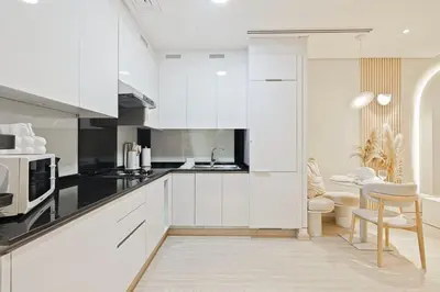 a white kitchen with white cabinets and a table at Tranquil Haven Near Burj Khalifa in Dubai