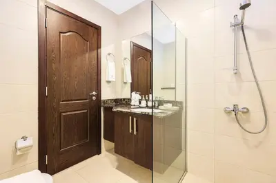 a bathroom with a shower and a wooden door at Stylish 4BR Family Villa Easy Access to Dubai Marina & Expo City in Dubai