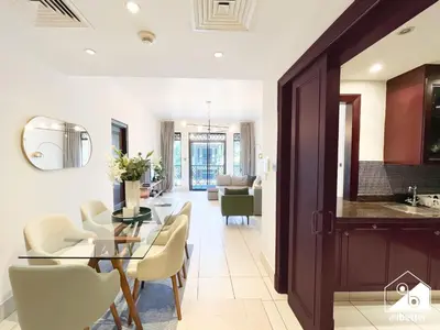 a dining room and living room with a glass table and chairs at Burj Views from Balcony l Chic 2BR in Downtown in Dubai