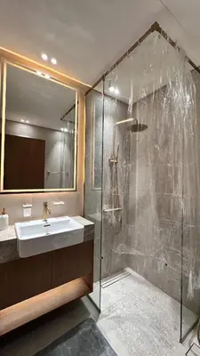 a bathroom with a sink and a glass shower at Lux Business Bay Studio with Jacuzzi & Canal View in Dubai