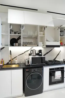 a kitchen with white cabinets and a black appliance at Lux Business Bay Studio with Jacuzzi & Canal View in Dubai