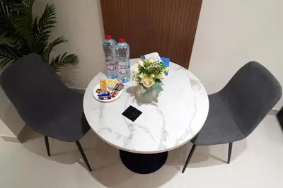 a white marble table with two chairs and drinks at Lux Business Bay Studio with Jacuzzi & Canal View in Dubai