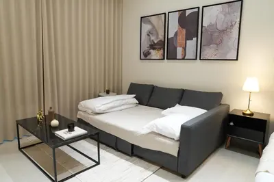 a living room with a bed and a table at Lux Business Bay Studio with Jacuzzi & Canal View in Dubai