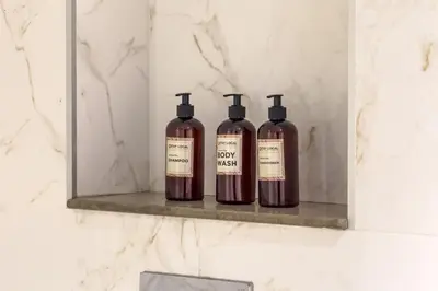 three bottles of wine sitting on a shelf in a bathroom at Modern Living with Canal Views, Near Burj Khalifa and World Trade Center in Dubai