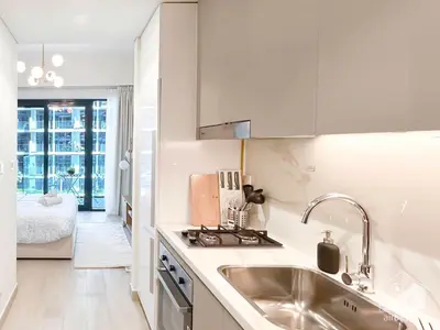 a white kitchen with a sink and a stove at Luxury & City Views Studio in Azizi Riviera in Dubai
