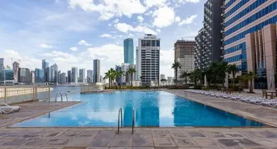 a large swimming pool in a city with buildings at Stylish 1BR Apt with Canal Views in Dubai