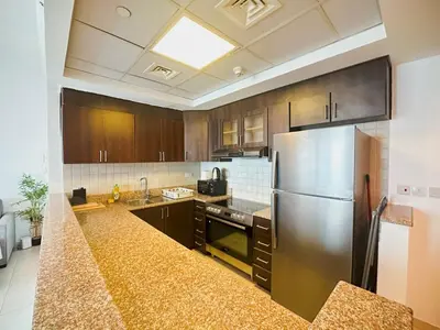 a kitchen with wooden cabinets and a stainless steel refrigerator at Stylish 1BR Apt with Canal Views in Dubai
