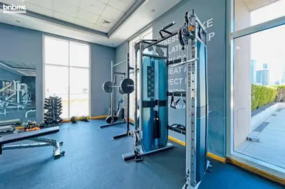 a gym with tread machines and a large window at Stylish 1BR Apt with Canal Views in Dubai