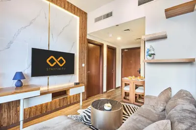 a living room with a couch and a tv at Cozy 1BR Vera Tower with Amazing Burj Khalifa View in Dubai