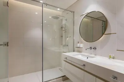 a bathroom with a shower and a sink and a mirror at 2 BR, private beach access, sea view, Emaar beach front in Dubai