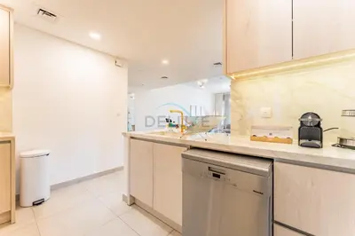 a kitchen with white cabinets and a dishwasher at Balcony Overlooking Community 2BR with Assistant Room, Minutes Away From the Beach, Madinat Jumeirah Living Rahaal 2, Jumeirah by Deluxe Holiday Homes in Dubai