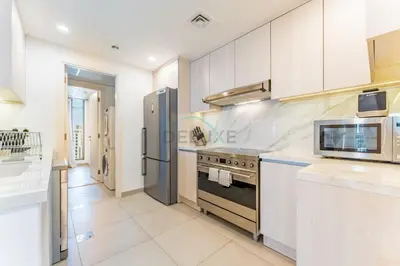 a kitchen with a stove and a refrigerator at Balcony Overlooking Community 2BR with Assistant Room, Minutes Away From the Beach, Madinat Jumeirah Living Rahaal 2, Jumeirah by Deluxe Holiday Homes in Dubai