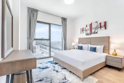 a white bedroom with a large bed and a window at VacayLettings - 1 BHK - Near Jebel Ali Port- IKEA - Metro 20 Min - Al Furjan in Dubai