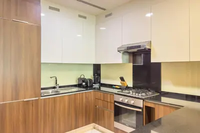 a kitchen with white cabinets and a stove top oven at Experience Modern Comforts Near Iconic Dubai Mall and Burj Khalifa in Dubai