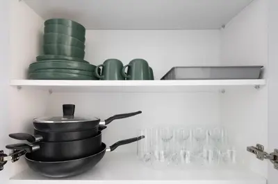 a kitchen shelf with a pot and plates and glasses at Stylish Studio Apartment in Binghatti Crystals in Dubai