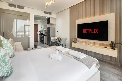a bedroom with a bed with a television on a wall at Stylish Studio Apartment in Binghatti Crystals in Dubai